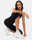 Woman wearing black high-waisted leggings and a matching sports top with white sneakers.