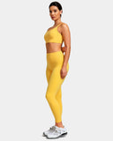 Woman wearing a yellow seamless sports bra and high waisted leggings with white sneakers.