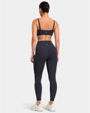 Rear view of a woman wearing a charcoal grey sports bra and high waisted seamless leggings.