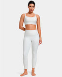 Woman wearing a white seamless sports bra and high waisted leggings activewear set.